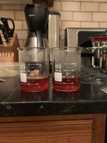 Two beakers, each filled to about the 88 ml mark with a translucent reddish liquid