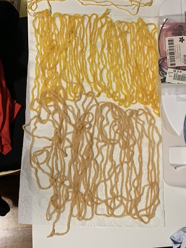 Two bunches of textile are laid out on a paper towel, the higher bunch is a vibrant orange/yellow and the lower is a paler brpwn/yellow