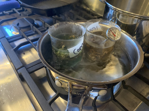Two beakers in pot of boiling water, each beaker contains a differently-labeled bundle of yarn (labels are not legible)