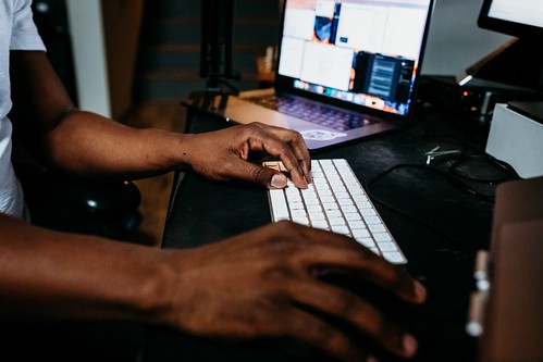 A person types on a keyboard next to a laptop - Job Jargon Definitions & Meaning