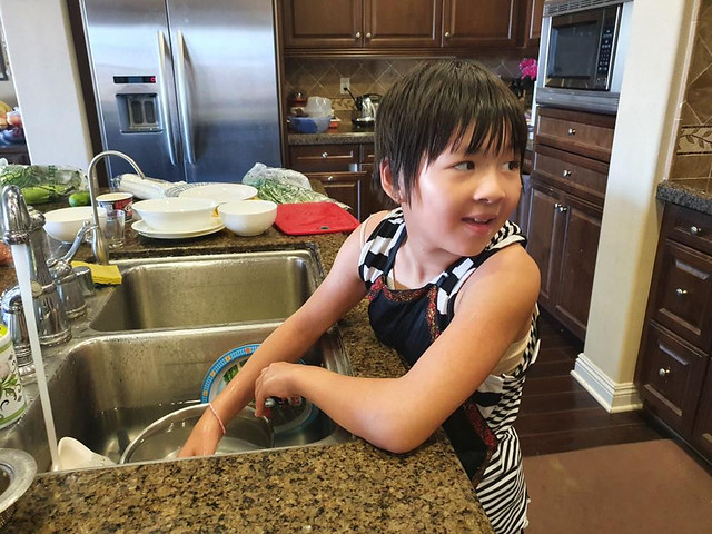 Jojo washes dishes while helping prepare a meal.