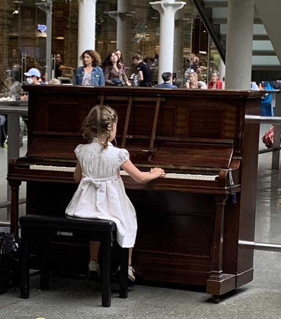 A young girl plays the “public” piano in the Saint Pancras train station in London.