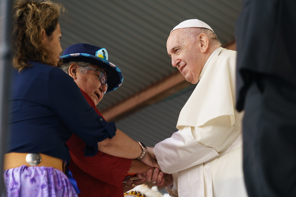 The hands of Pope Francis and two women hold together