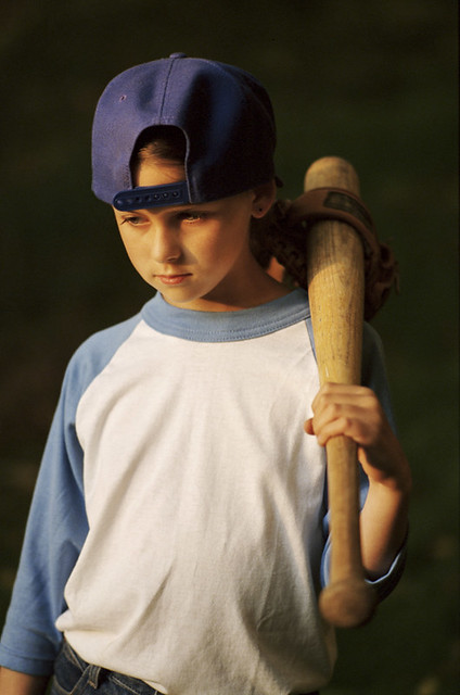 Portrait of young girl with serious expressions with baseball and mitt on shoulder