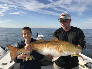 Photo of boy and man holding a large fish in a boat