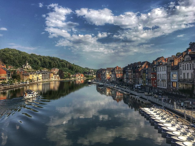 Reflections of clouds, hills and houses in the water of Dinant in beautiful Belgium
