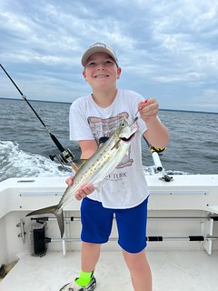  Photo of boy on a boat holding a striped bass
