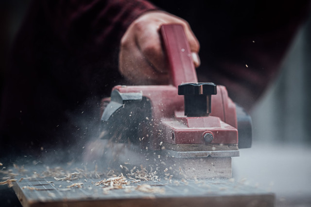 Close-up of an electric planer in action. Dust and pieces of wood flying everywhere