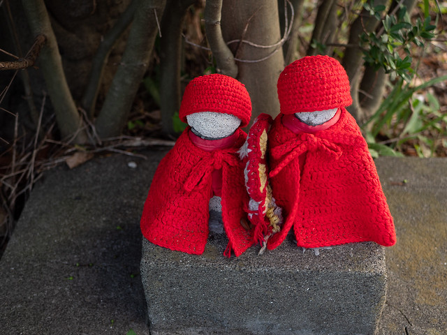 small stone statues wearing red