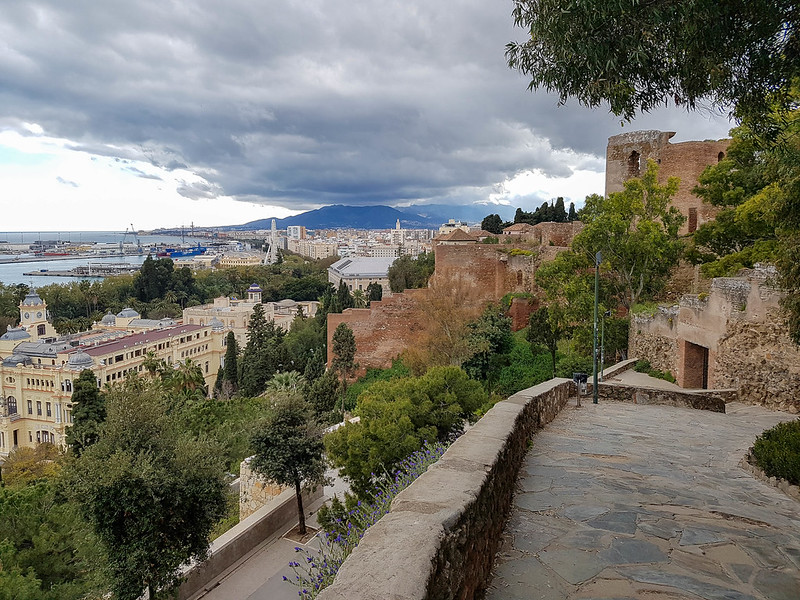 A photo of the wall of the Alcazaba on the right hand side, and the view of the city from above, on the left.
