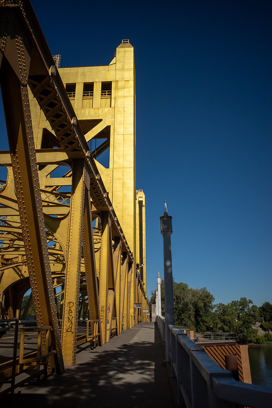 A metallic yellow bridge, photographed from the side of the bridge
