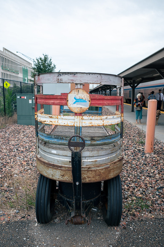 A weathered pull cart, with a rusty Amtrak pointless arrow logo, red white and blue