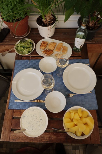 Mehliert gebratene Stücke vom Kabeljau mit Salzkartoffeln und Kräuterjoghurt sowie Gurkensalat (Tischbild)