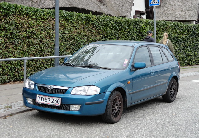 1998 MAZDA 323 1.8 TB57230 is still on the roads of Denmark and displays a numberplate damaged by reversing tow bals