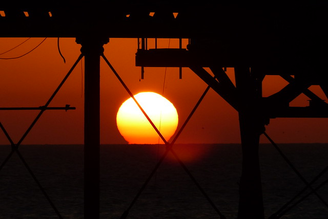 Silhouette sunrise through the pier supports