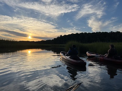 2 kayaks and kayers on the water facing the sunset.