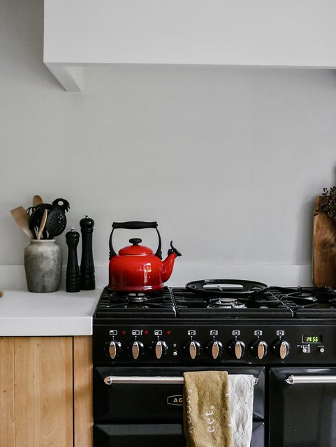 Le Creuset rode waterketel peper en zoutmolen zwart houten snijplank dadeltak linnen theedoek met tekst landelijke vaas met lepels en keukengerei