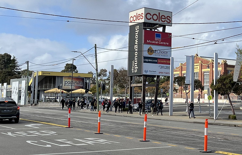 A crowd of tram passengers walking along the road to find the nearest open Showgrounds entrance. Some people are heading to the (closed) gate 11.