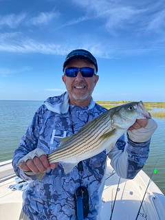 Photo of man on a small boat holding a striped bass