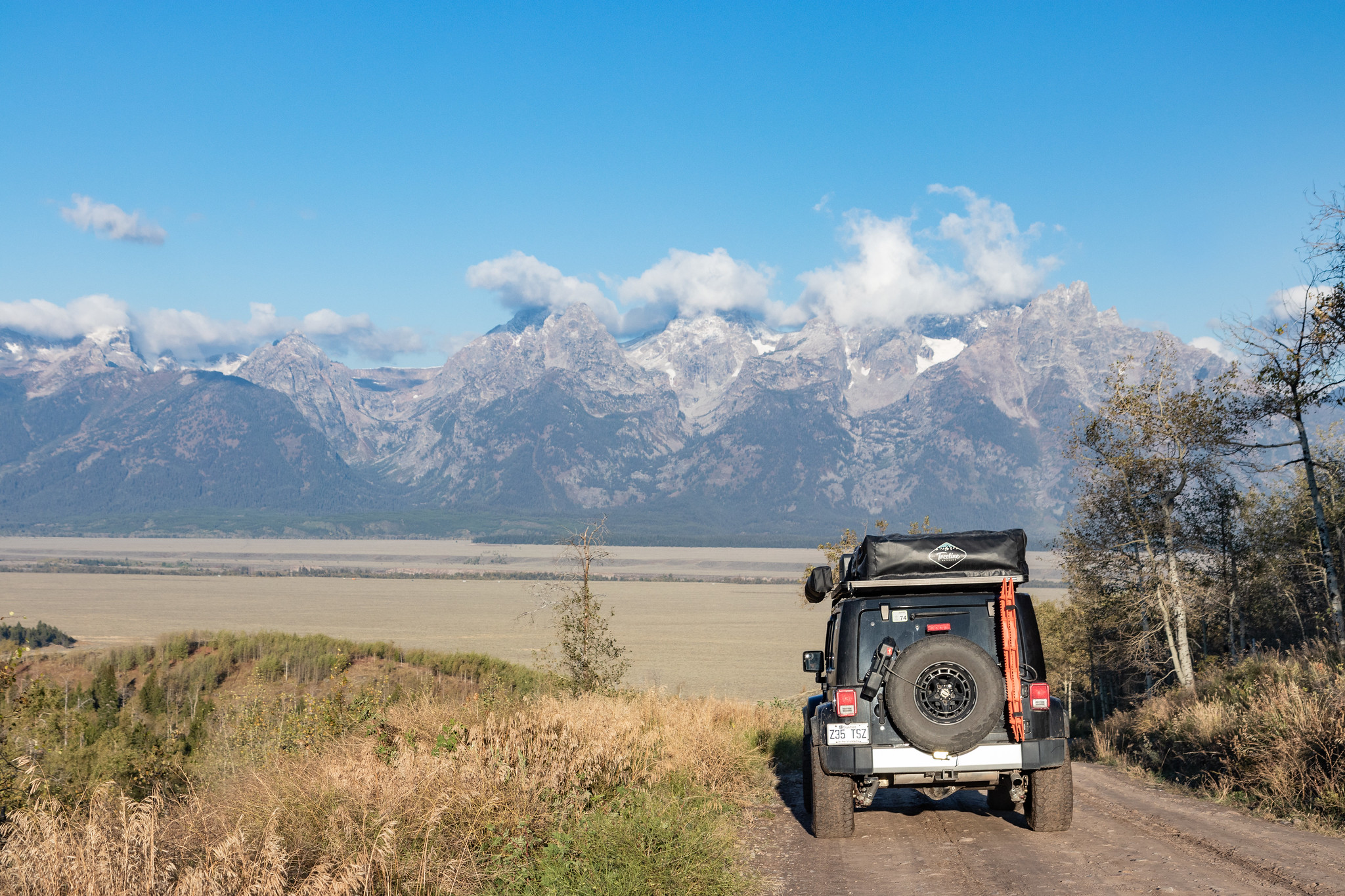 Un Jeep Overland sur une piste face aux montagnes du parc national de Grand Teton