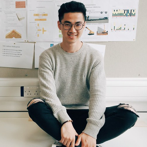 Jianan sits cross-legged on a table against a wall of architectural sketches