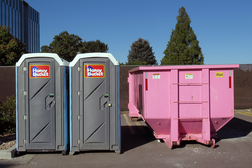 Pink Dumpster with Two Out Houses