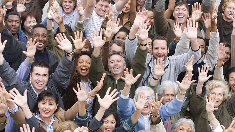 A large group of diverse people with their hands in the air.