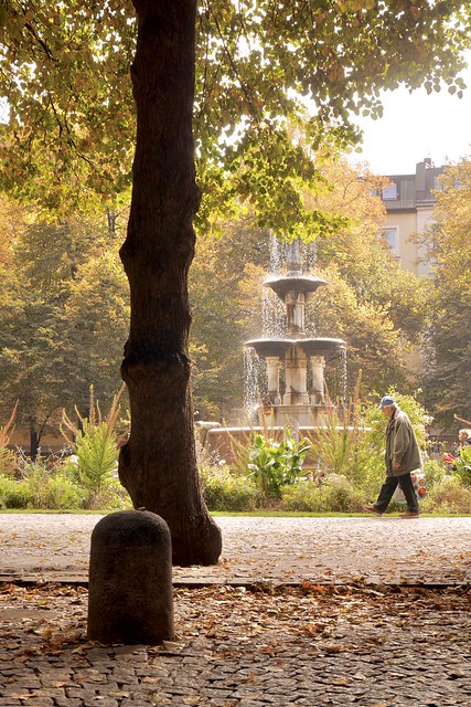 Autumn, fountain and passerby