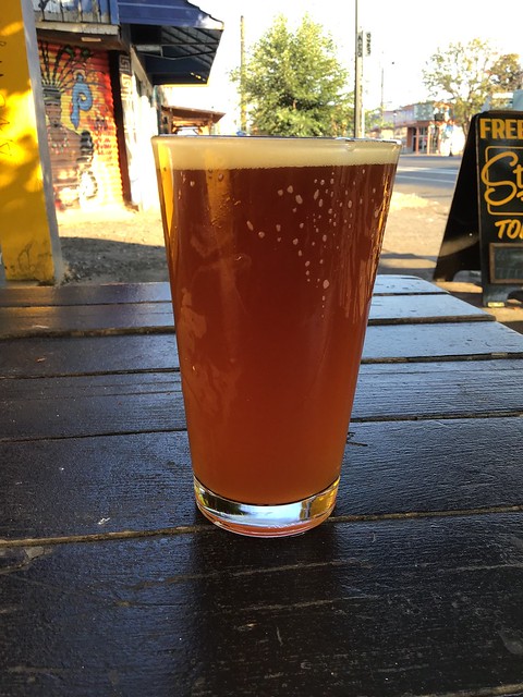 Mac & Jack's amber ale in a pint glass on a table outside.