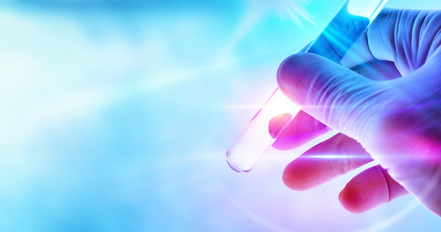 Hand of a scientist with test tube on blue background