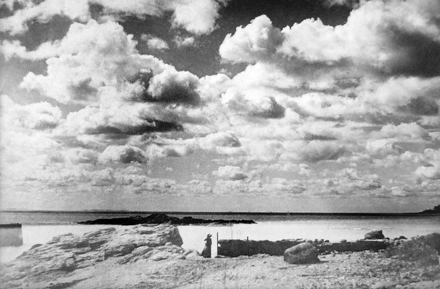 A lone woman in a dress stands at the Anchor Beach and takes in the amazing sight of the massive cumulus clouds hovering over Long Island Sound that day. Woodmont Connecticut. Circa 1915.