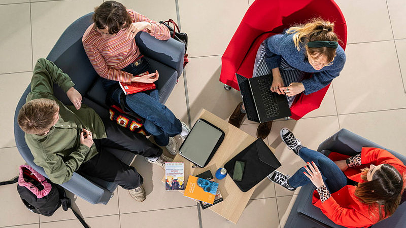 An overhead view of four people sat across from each other attending a meeting.