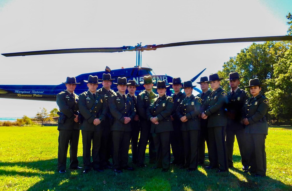 Photo of uniformed officers posing in front of a parked helicopter