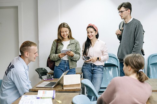 5 students sit and stand around a classroom table
