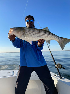 Photo of man in a boat holding a striped bass