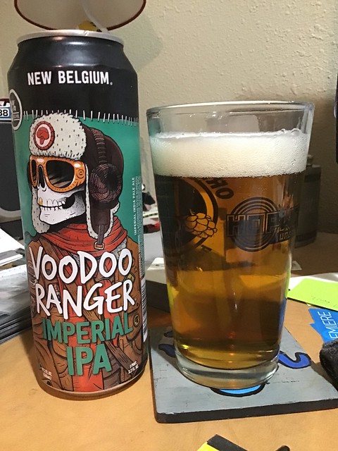 Voodoo Ranger IIPA can next to a glass of same, on a desk. 