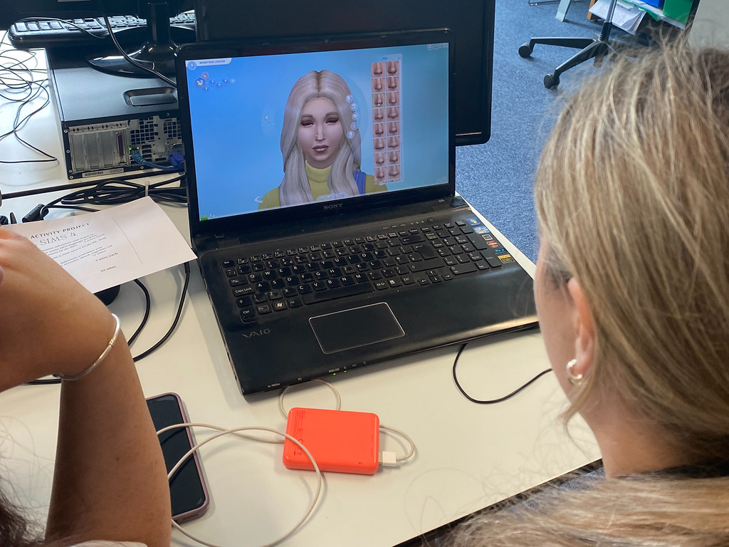 A young woman looking at a virtual woman on a laptop