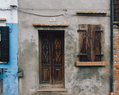 Old wooden door and shutters on a gray wall in Burano