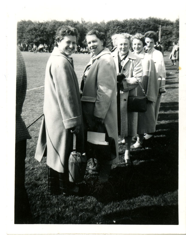 Five ladies in winter coats standing at side of playing pitch. On rear: ‘Amsterdam 1959’