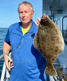 Photo of man on a boat holding a flounder
