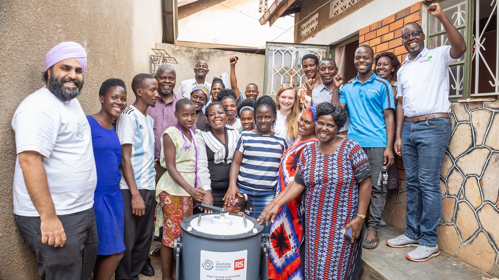 Nav Sawhney pictured with families in Uganda trialing the Divya hand-cranked washing machine. 