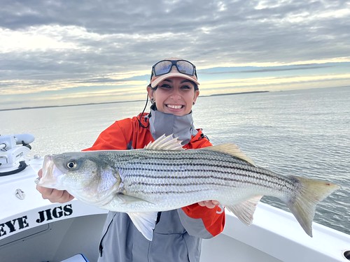 Photo of woman on a charter boat holding a large striped bass