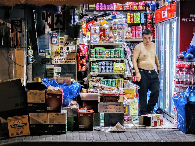 It was 27℃ (80℉) in Shanghai on November 12, 2022. I was shooting street scenes in short sleeves and shorts and saw this grocery shop owner without a top.