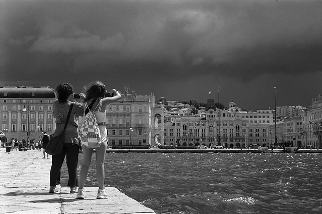 Two taking sunny pictures of a storm approaching