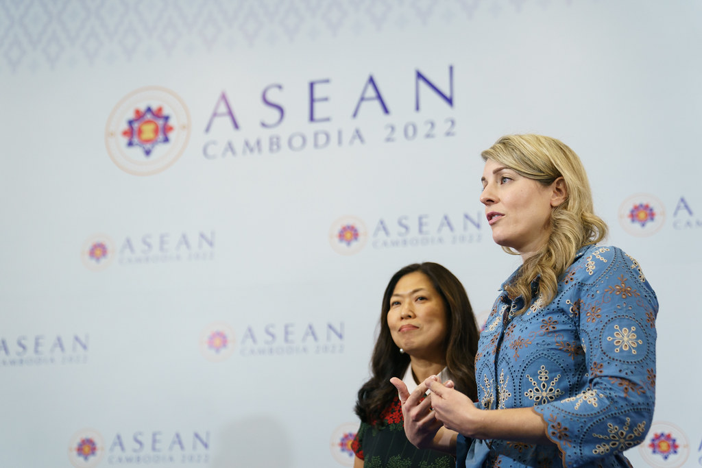 Minister Joly speaking and Minister Ng stands beside her, the words ASEAN CAMBODIA 2022 behind them
