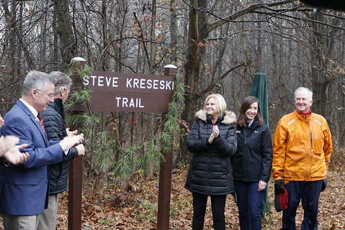 Photo of people unveiling a sign along a wooded trail