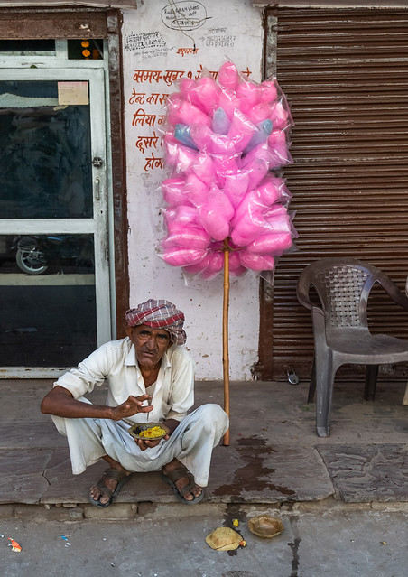 Rajasthani man eating in the street and selling pink sweets, Rajasthan, Pushkar, India