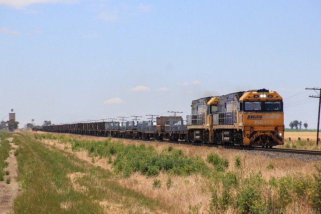 NR122 and NR72 haul a long empty NY3 steel train down grade from Jung into Dooen