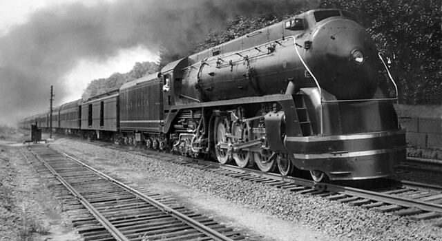 New Haven Railroad Baldwin I-5 class 4-6-4 streamlined Hudson steam locomotive # 1404 with its passenger train is seen operating on the Shore Line with a plumb of smoke behind at an unknown location, ca 1940's