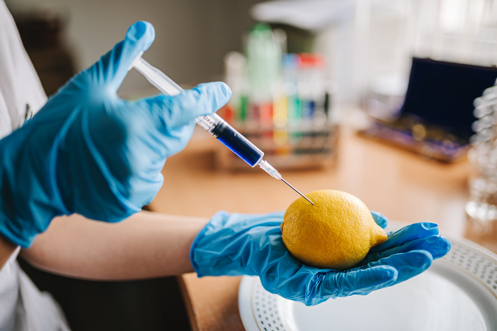 Scientist injecting a lemon with a colorful chemical